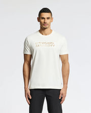 The man, with short dark hair and a neutral expression, stands against a plain white background wearing sleek black pants and the MENS BERNI EMBROIDERED WORDMARK GRAPHIC TEE - B6U417F200 by Psycho Bunny, featuring soft Pima cotton and a gold embroidered logo.