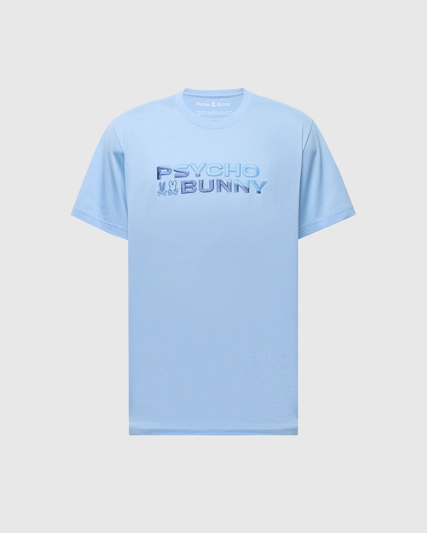 The MENS BERNI EMBROIDERED WORDMARK GRAPHIC TEE by Psycho Bunny is a light blue Pima cotton tee with "Psycho Bunny" text in darker blue across the chest and a small embroidered bunny and skull graphic. This short-sleeve, crew-neck T-shirt is breathable and offers both style and comfort.