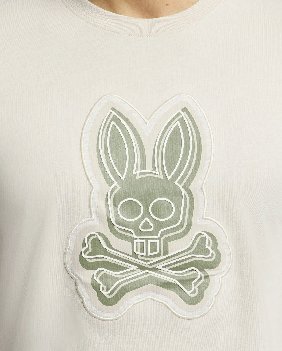Close-up of the MENS SYDNEY GRAPHIC TEE by Psycho Bunny, featuring a stylized bunny with a skull face and crossbones, expertly outlined in gray and white. This edgy Pima cotton shirt embodies graphic print flair.