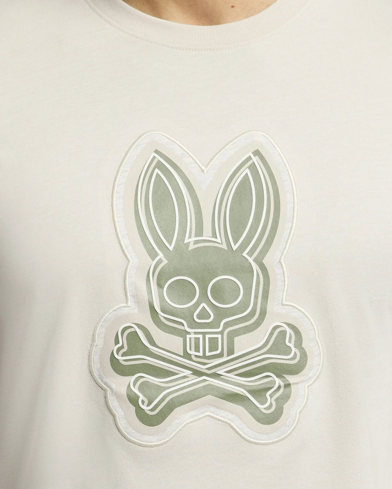Close-up of the MENS SYDNEY GRAPHIC TEE by Psycho Bunny, featuring a stylized bunny with a skull face and crossbones, expertly outlined in gray and white. This edgy Pima cotton shirt embodies graphic print flair.