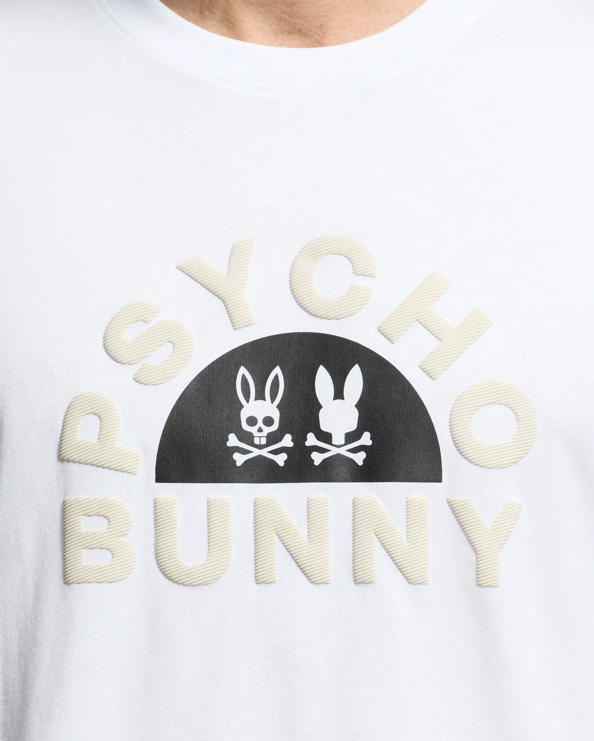 The MENS GOLDIE GRAPHIC TEE by Psycho Bunny is made from luxurious Peruvian cotton, with "PSYCHO BUNNY" in curved block letters and a black semicircle featuring two stylized bunny faces above crossed bones, one with hollow eyes.