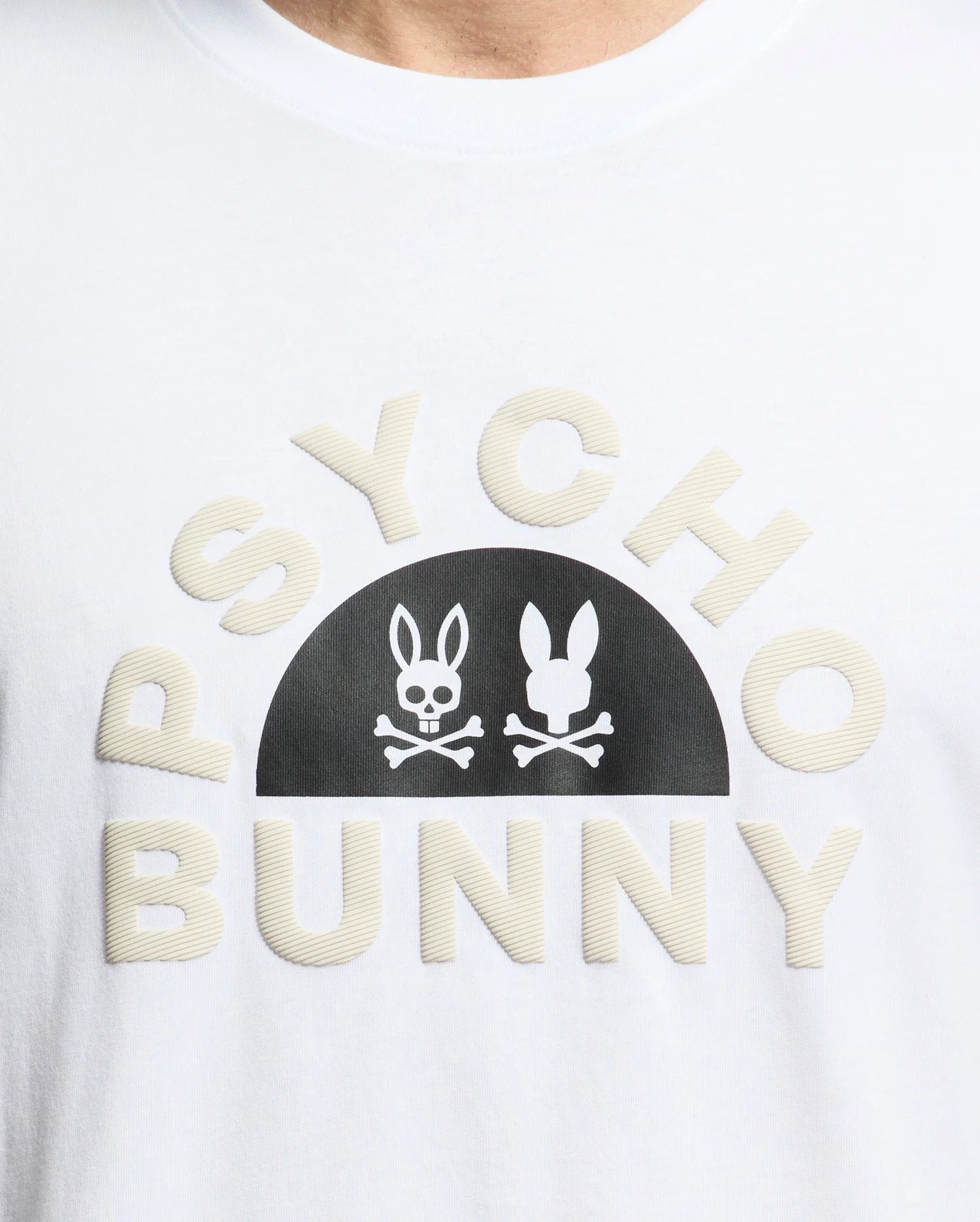The MENS GOLDIE GRAPHIC TEE by Psycho Bunny is made from luxurious Peruvian cotton, with "PSYCHO BUNNY" in curved block letters and a black semicircle featuring two stylized bunny faces above crossed bones, one with hollow eyes.