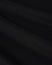Close-up image of the MENS MELVIN GRAPHIC TEE - B6U663C200 by Psycho Bunny, showcasing its smooth, black Pima cotton fabric with a slightly textured surface. The tee is neatly folded, creating gentle, horizontal ridges and a subtle play of light and shadow.