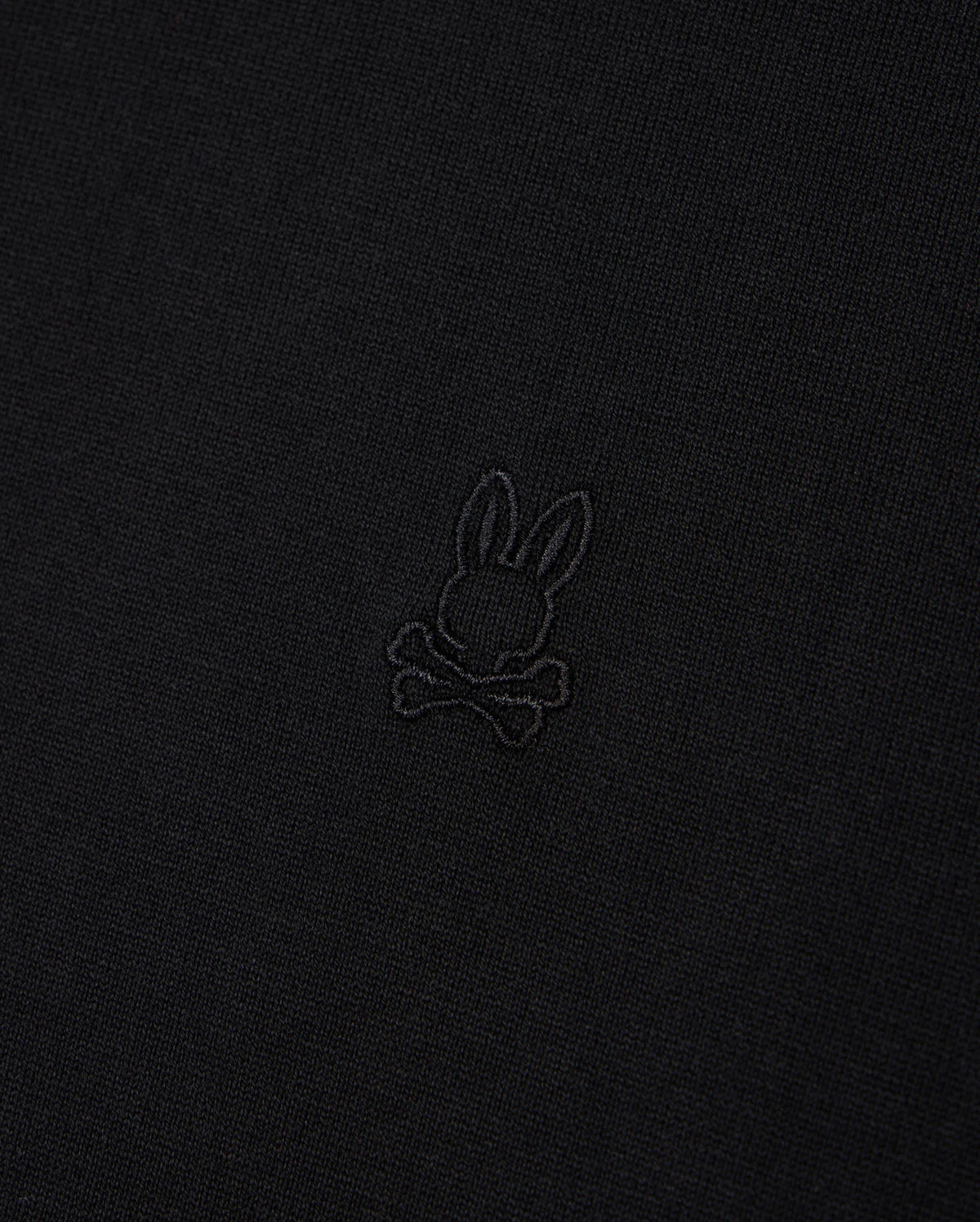 A close-up image of Psycho Bunny's MENS DUKE OVERSIZED TEE - B6U742D200, made from heavyweight Pima cotton fabric featuring an embossed rabbit head with long ears positioned above a pair of crossed bones. The subtle design blends slightly with the fabric, providing a relaxed and comfortable fit.