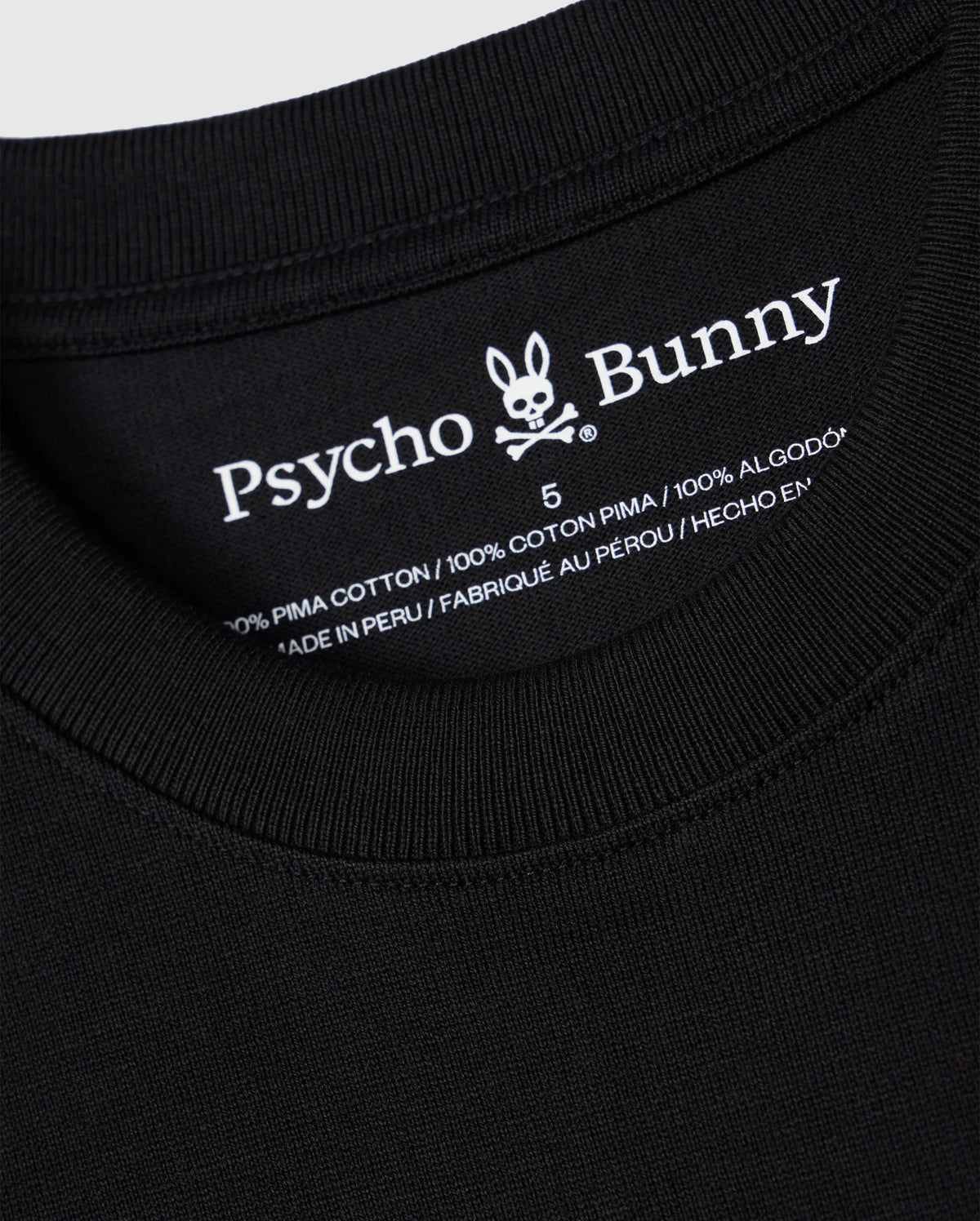 Close-up of the neckline and inner clothing label of a black MENS DUKE OVERSIZED TEE - B6U742D200 from Psycho Bunny. The label shows the brand name and logo, detailing "100% heavyweight Pima cotton," "Made in Peru," and featuring an embroidered chest bunny on this relaxed fit design.