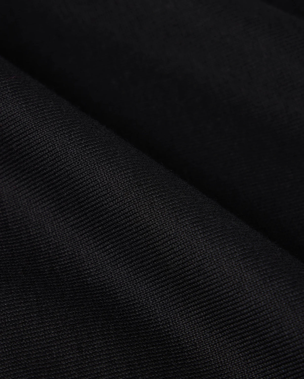 Close-up image of the heavyweight Pima cotton fabric of the Psycho Bunny MENS DUKE OVERSIZED TEE - B6U742D200, showcasing its fine, woven details and subtle lines. The fabric appears to be slightly folded, creating small, diagonal ridges and shadows.