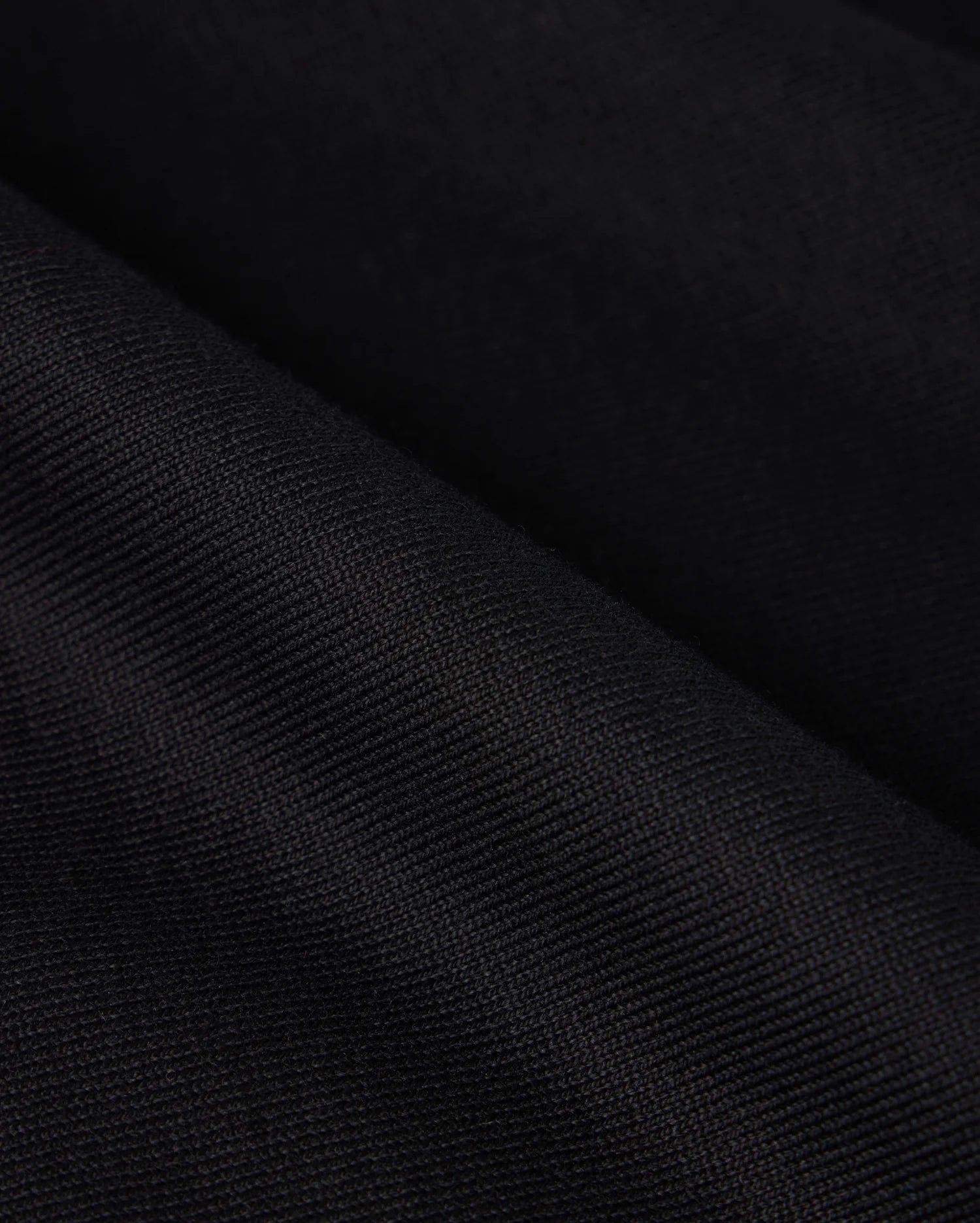 Close-up image of the heavyweight Pima cotton fabric of the Psycho Bunny MENS DUKE OVERSIZED TEE - B6U742D200, showcasing its fine, woven details and subtle lines. The fabric appears to be slightly folded, creating small, diagonal ridges and shadows.