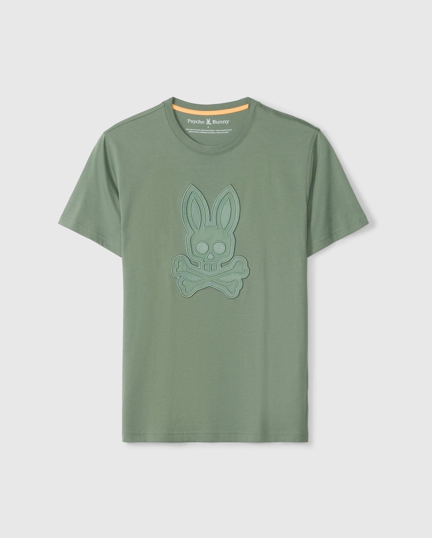 The Psycho Bunny MENS MALTON GRAPHIC TEE - B6U795D200 is a green short-sleeve graphic tee crafted from luxurious Pima cotton. It features an embroidered bunny skull and crossbones on the chest, along with a stylish orange accent on the inner neckline of the crew neck. Made in Peru, this tee offers exceptional quality and comfort.