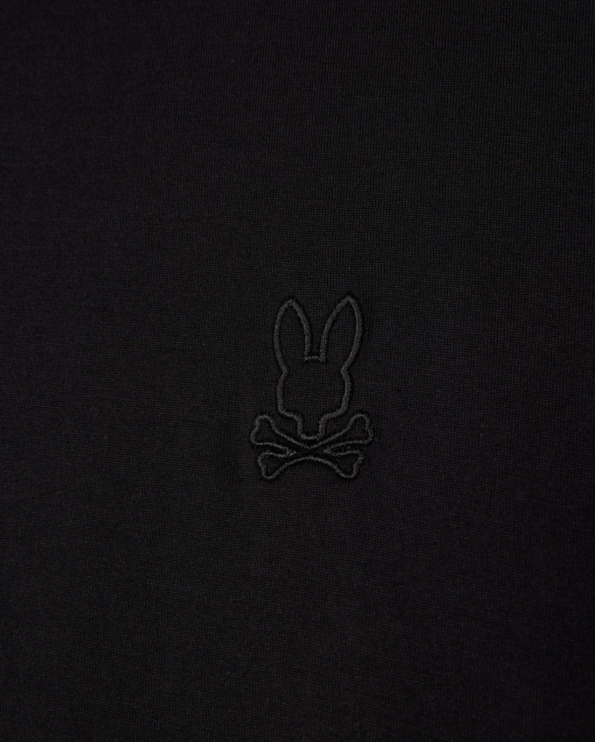 Close-up of the Psycho Bunny MENS JAMES PREMIUM CREW NECK TEE (B6U952D200), crafted from soft Pima cotton, featuring a black embroidered bunny head above crossbones logo, offering a playful twist on the traditional skull and crossbones symbol in the center.