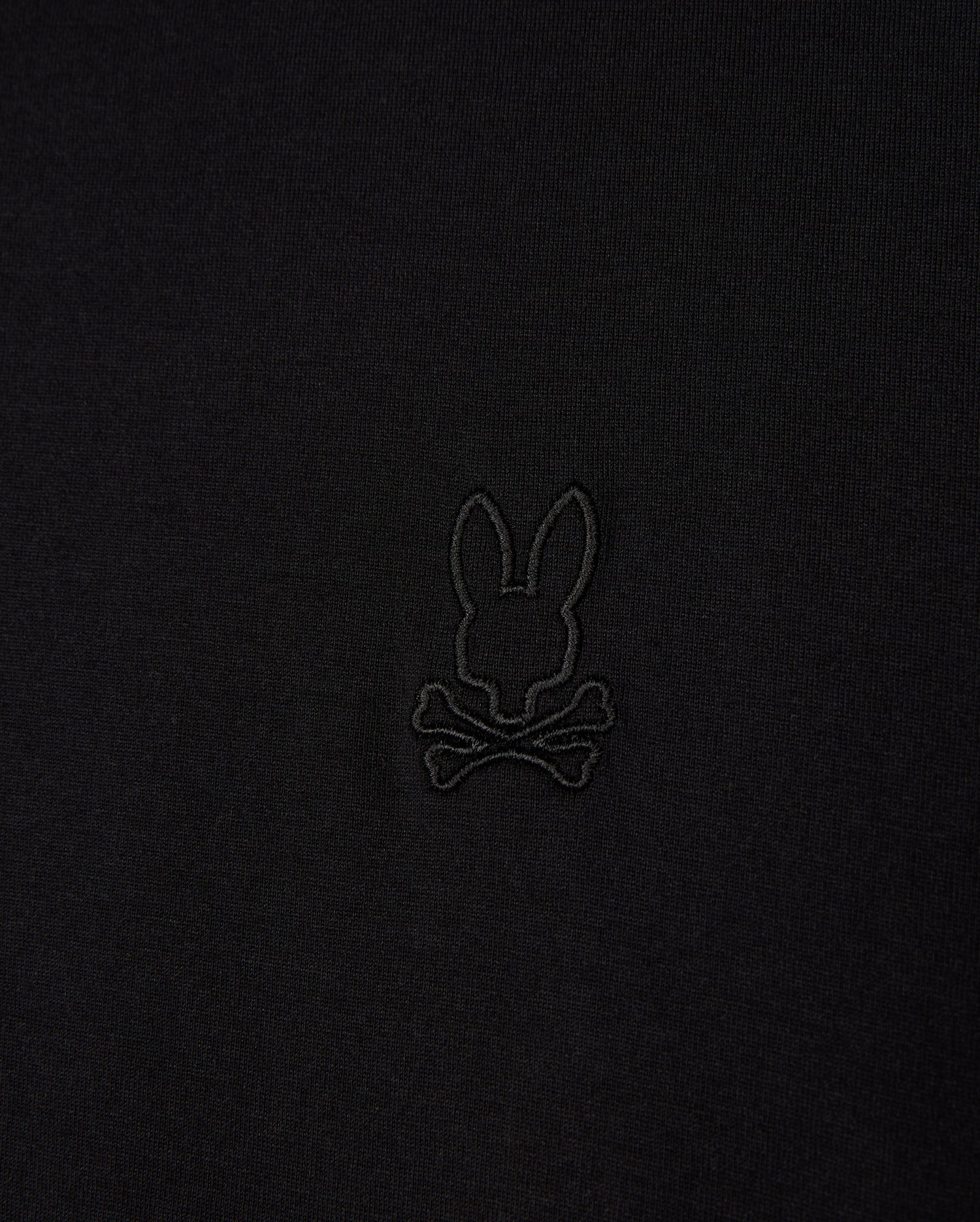Close-up of the Psycho Bunny MENS JAMES PREMIUM CREW NECK TEE (B6U952D200), crafted from soft Pima cotton, featuring a black embroidered bunny head above crossbones logo, offering a playful twist on the traditional skull and crossbones symbol in the center.