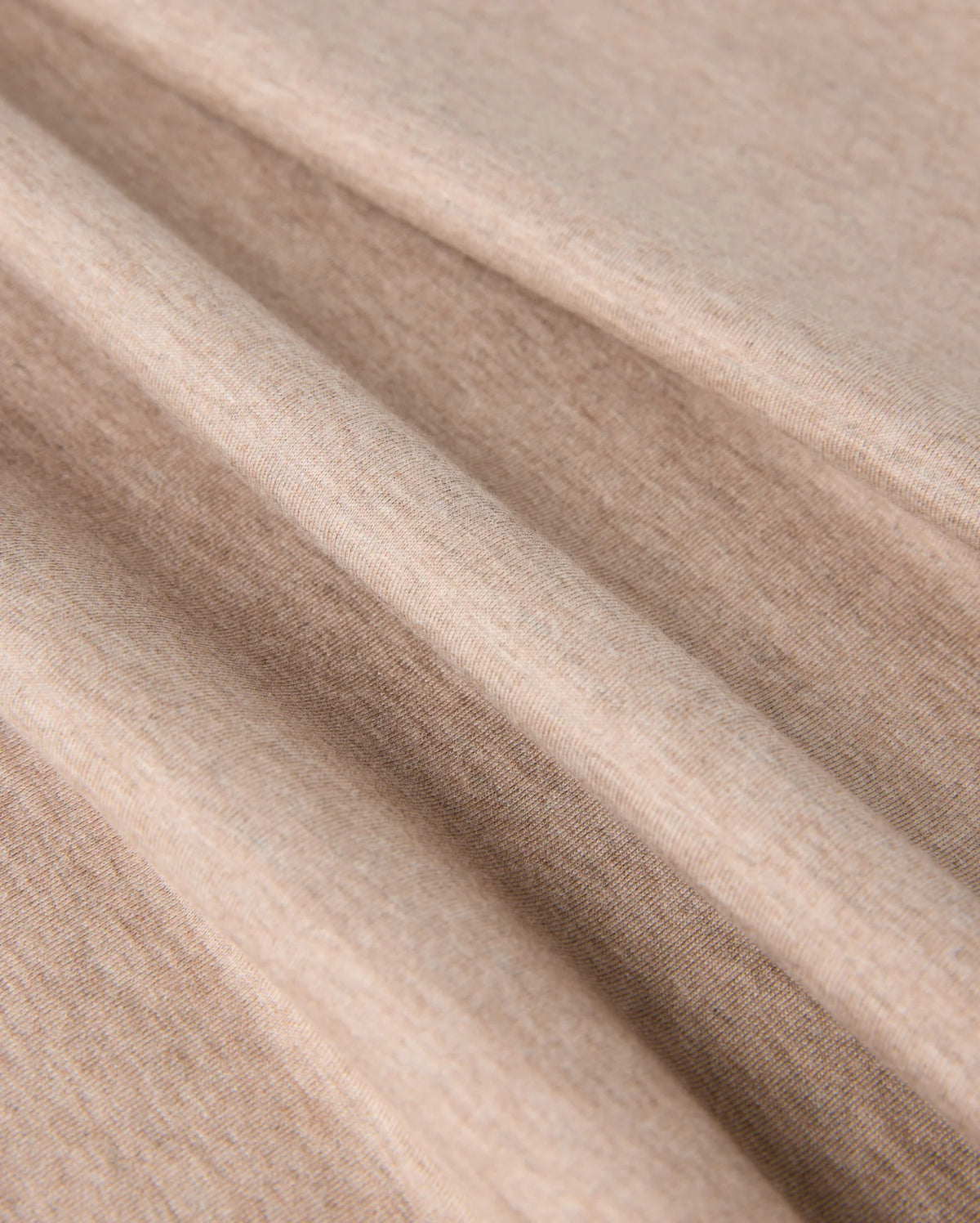 Close-up image of soft, light brown fabric with visible texture. The fabric appears to be folded in several smooth, gentle creases, showcasing its flexibility and softness. Made from premium Pima cotton, the material looks like it could be perfect for the MENS JAMES PREMIUM CREW NECK TEE - B6U952D200 by Psycho Bunny.