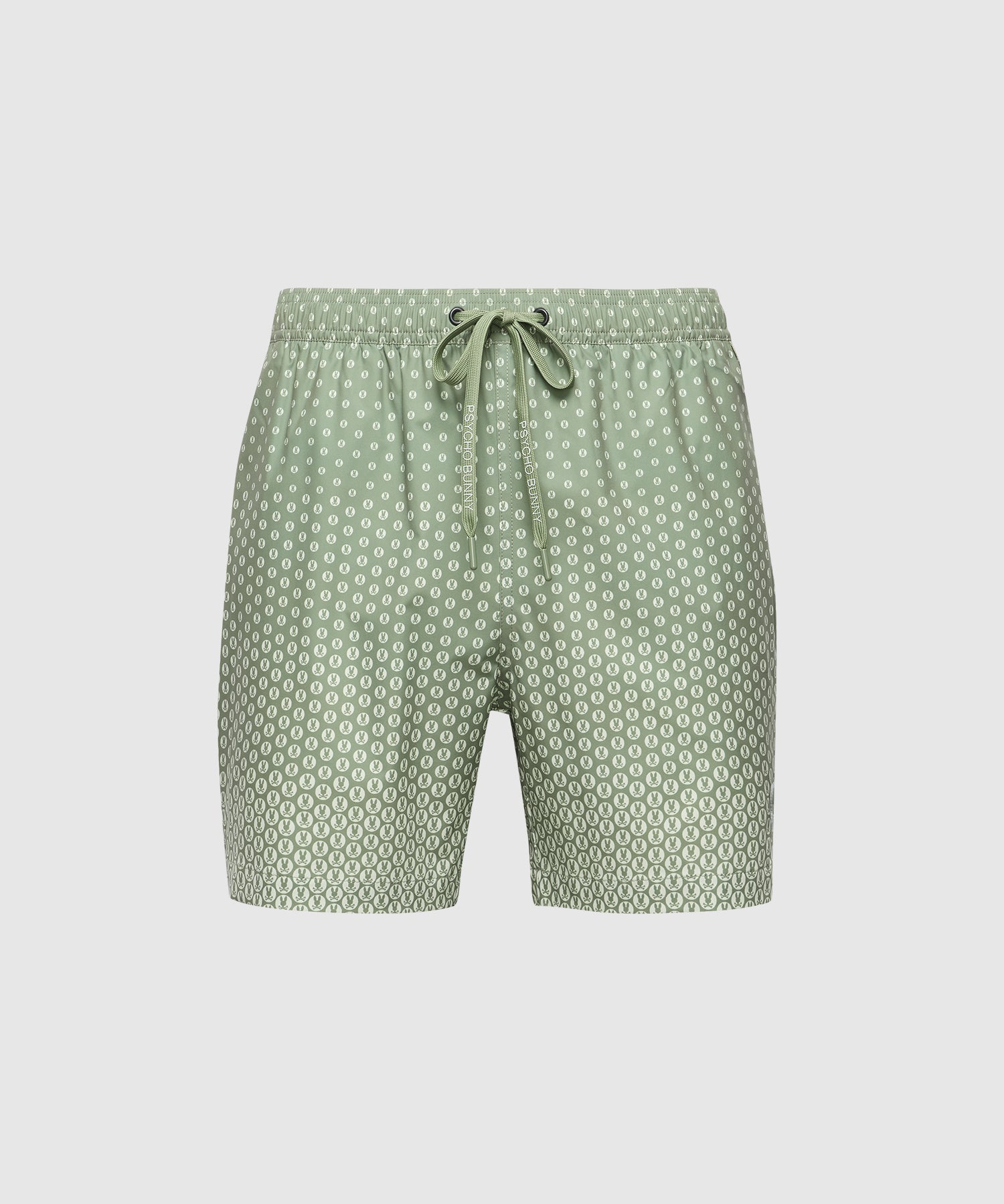 The Psycho Bunny MENS BENDIGO ALL OVER PRINTED SWIM TRUNK (B6W619F200) showcases green shorts with a white geometric bunny pattern, an elastic drawstring waistband, and quick-dry fabric. Displayed on a plain white background.
