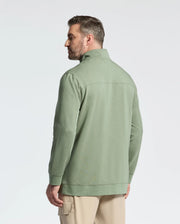 A man with short hair faces away, wearing a Psycho Bunny light green collared jacket (MENS BIG AND TALL DESERT 1/4 MOCK ZIP - B9S488F200) and beige cargo pants against a plain white backdrop.