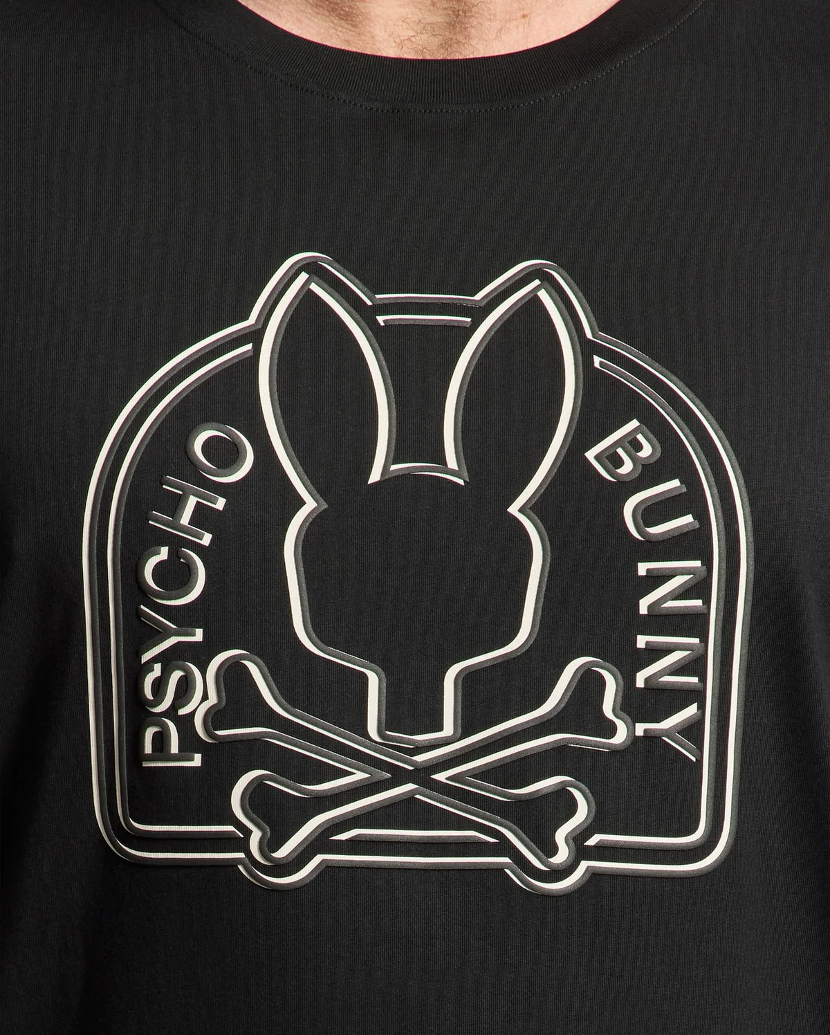 Close-up of the MENS BIG AND TALL MELBOURNE GRAPHIC TEE crafted from Peruvian Pima cotton. This black Psycho Bunny T-shirt features an eco-friendly, large graphic of a rabbit head above crossed bones with "Psycho Bunny" encircling the design.