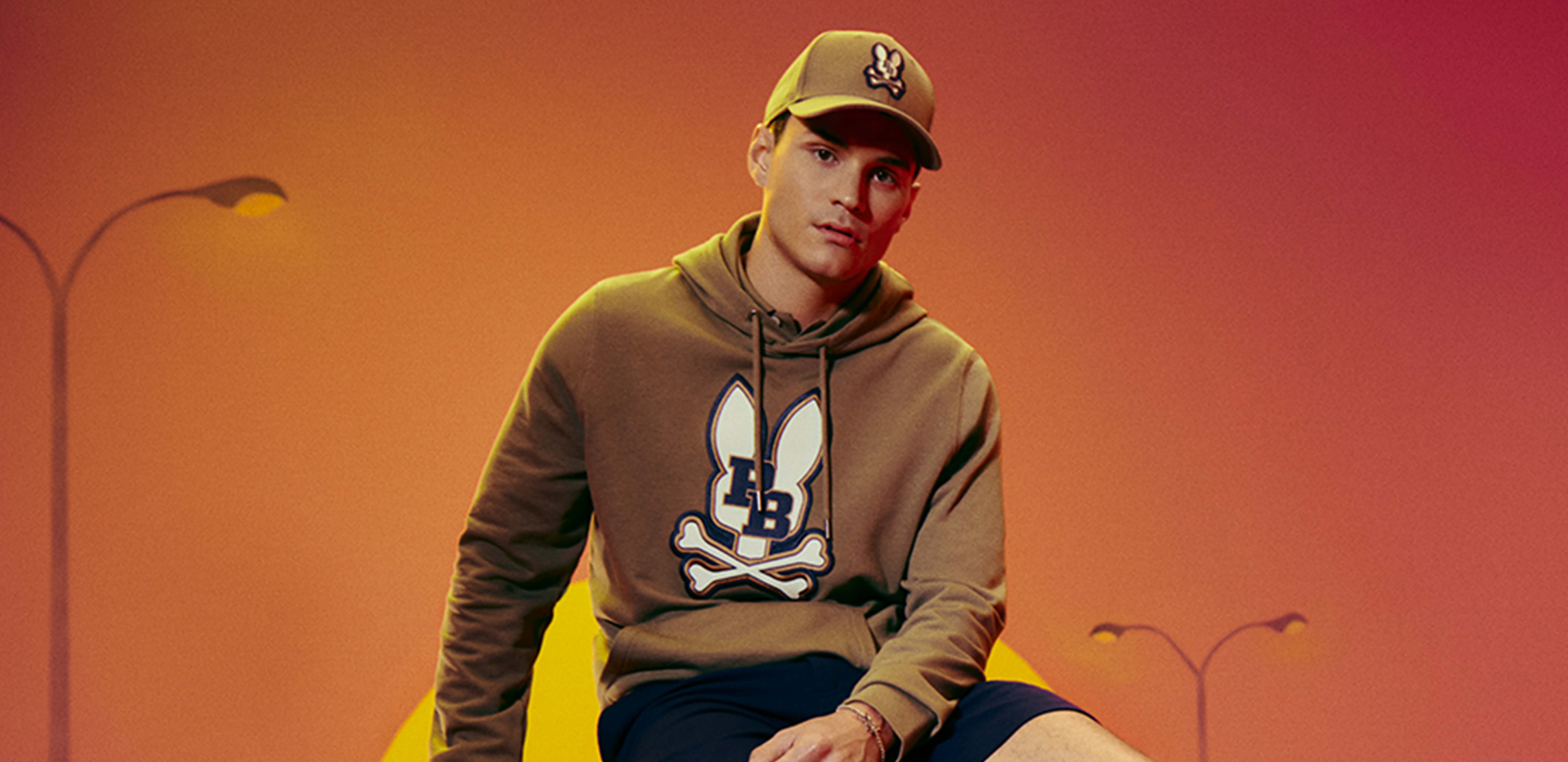Person wearing a hoodie with a logo against an orange background