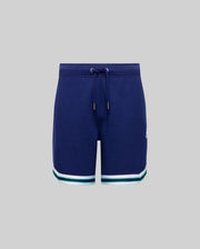 The KIDS BASIL TAPED SHORT (KB0900003) by Psycho Bunny features a navy blue cotton-modal blend with a drawstring waist and white and green striped hems, shown against a plain gray background.