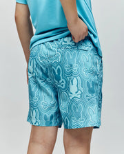 A person wears Psycho Bunny KIDS CHUCK ALL OVER PRINT LIGHTWEIGHT SWIM TRUNK (KB1000002), featuring a repeating Bunny print and quick-dry fabric, with one hand resting on their hip.