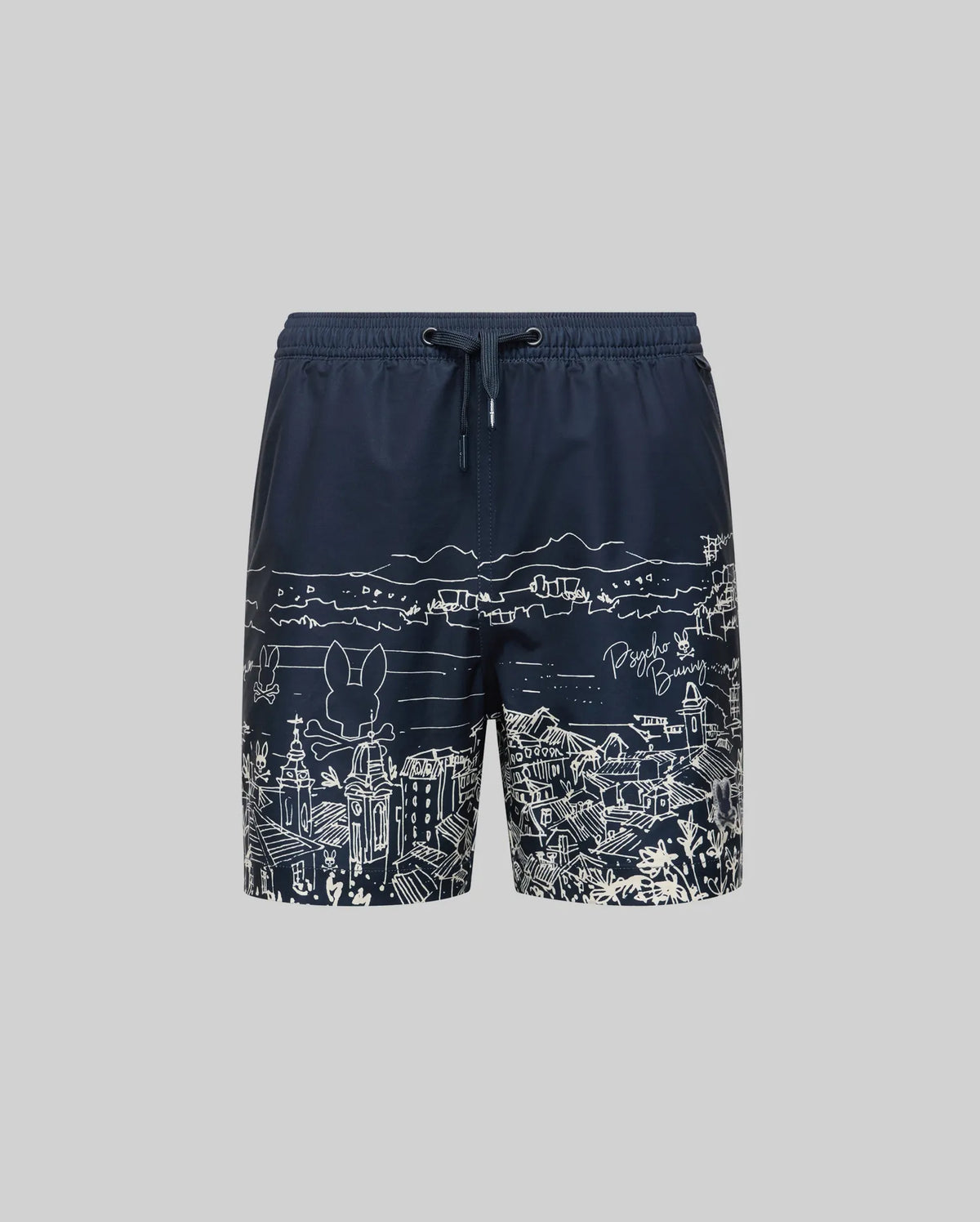 The Psycho Bunny KIDS NAXOS SWIM TRUNK (KB1000006) is navy blue with white line-art of Greek island cityscapes—buildings and mountains—and features a drawstring waistband, shown against a plain grey background.