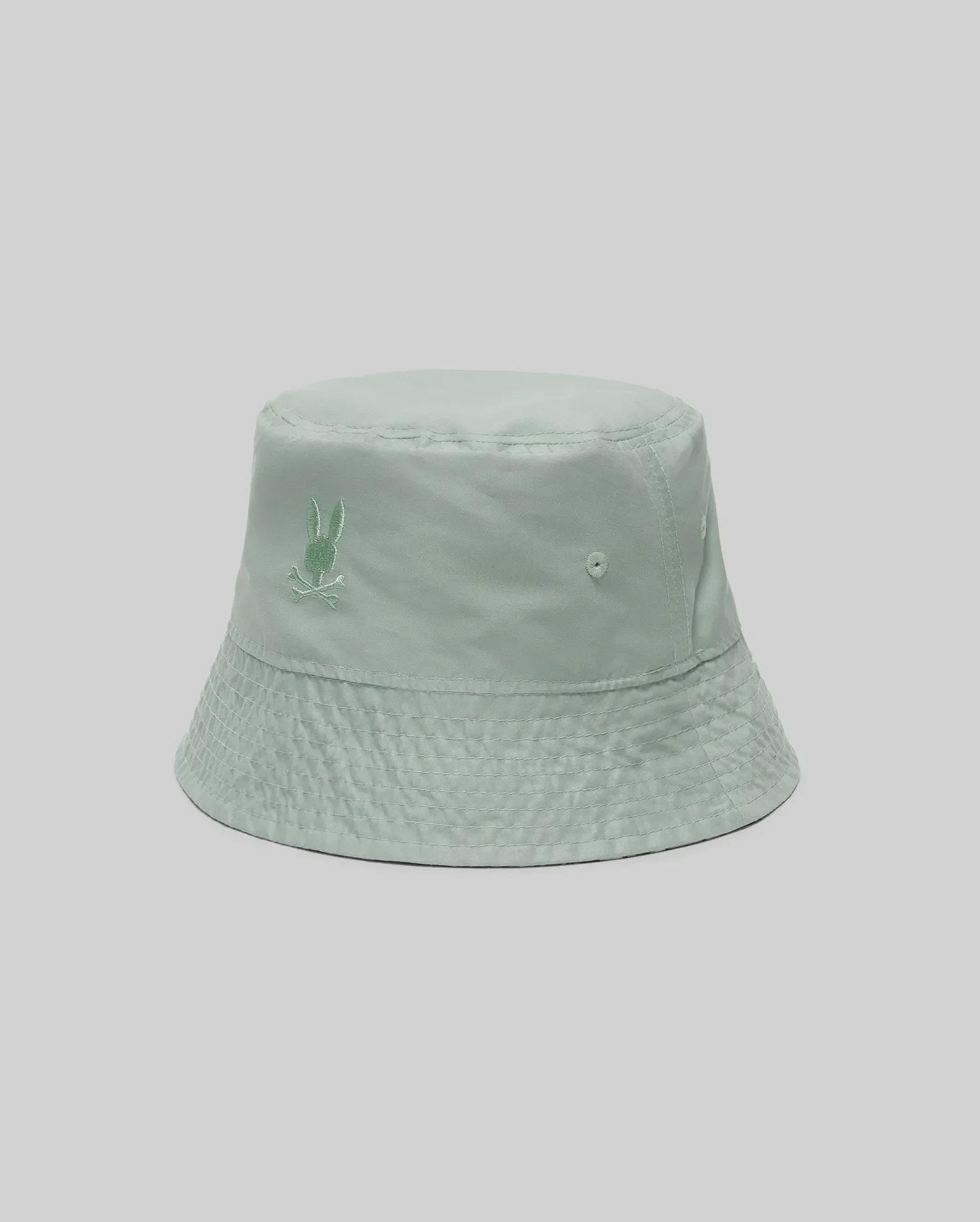 The KIDS CHUCK REVERSIBLE BUCKET HAT - KO1500015 by Psycho Bunny features light green fabric with a small embroidered bunny logo on the front, shown against a plain light grey background.