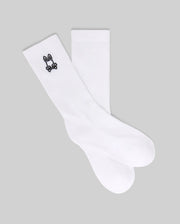 The Psycho Bunny KIDS 3 PACK SPORT SOCK (KO2200001) includes white crew socks made with soft Pima cotton and spandex, each featuring a small black bunny skull and crossbones logo near the top. Displayed on a gray background.