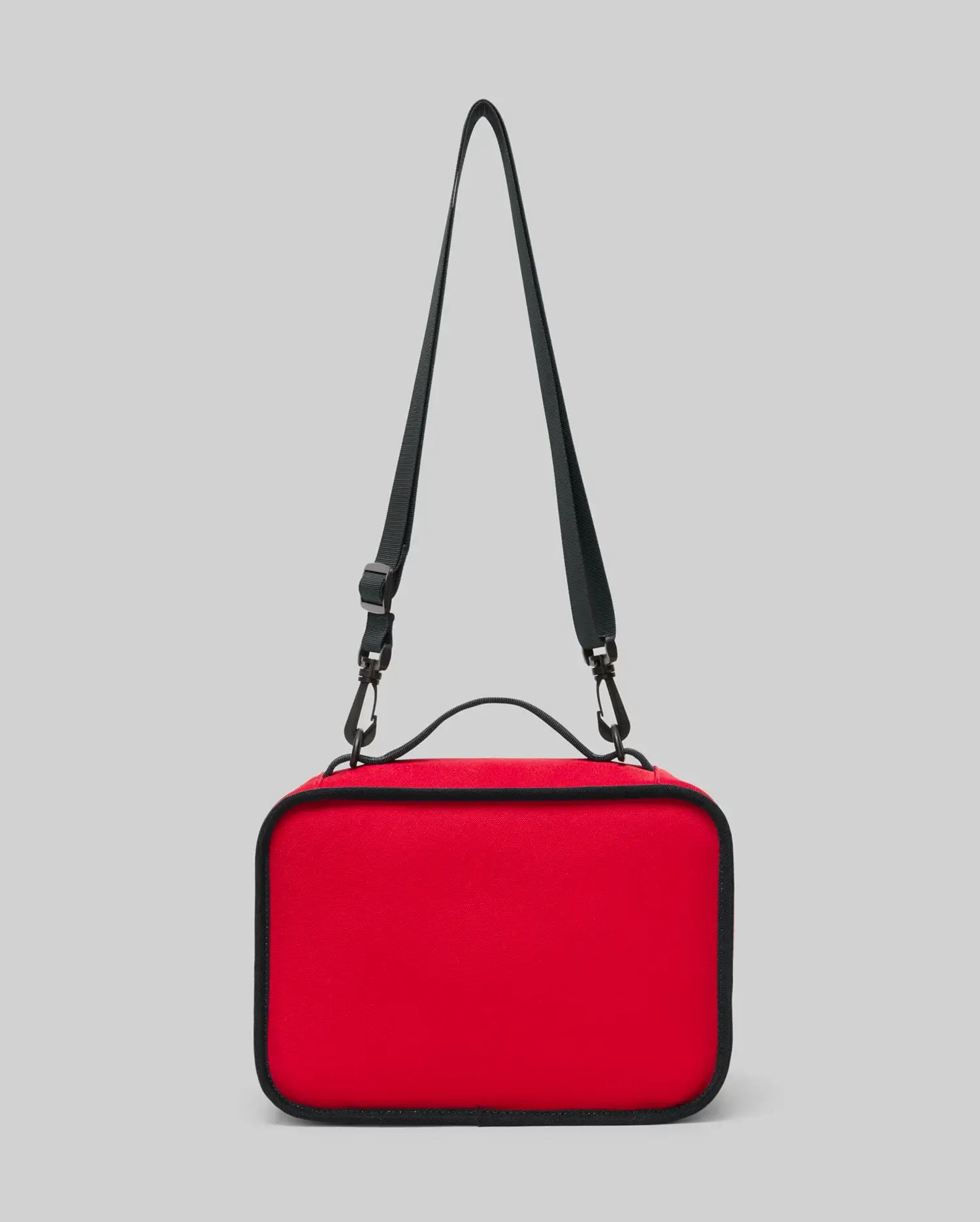 The PSYCHO BUNNY LUNCH BOX - KO2400002 by Psycho Bunny is a rectangular red insulated lunch box featuring black edges, a top black handle, and an adjustable shoulder strap, shown against a plain gray background.
