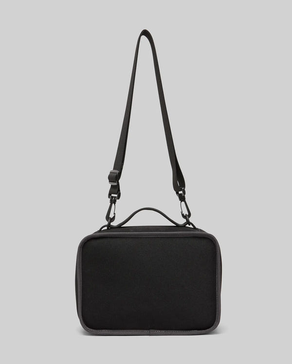 The PSYCHO BUNNY LUNCH BOX - KO2400002 by Psycho Bunny is a black rectangular shoulder bag with a top handle and adjustable strap, shown against a plain light gray background—ideal as an insulated lunch box.