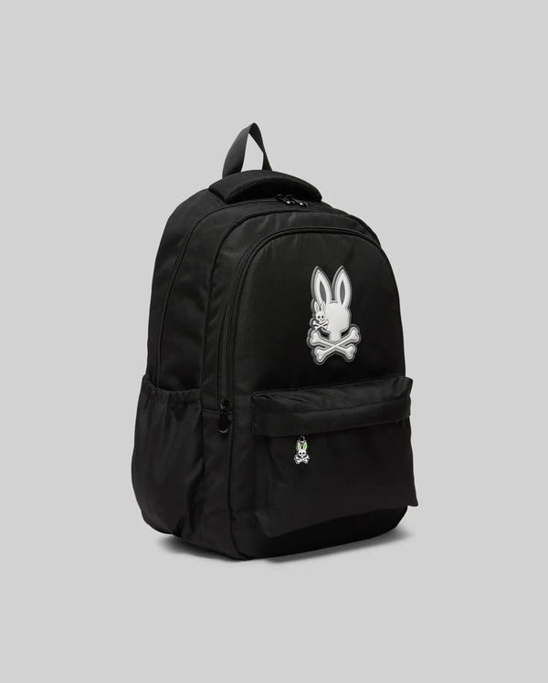The KIDS PSYCHO BUNNY BACKPACK - KO2400004 by Psycho Bunny features a large white bunny skull and crossbones logo on the front pocket, crafted from durable canvas with padded, adjustable shoulder straps. Shown against a gray background.