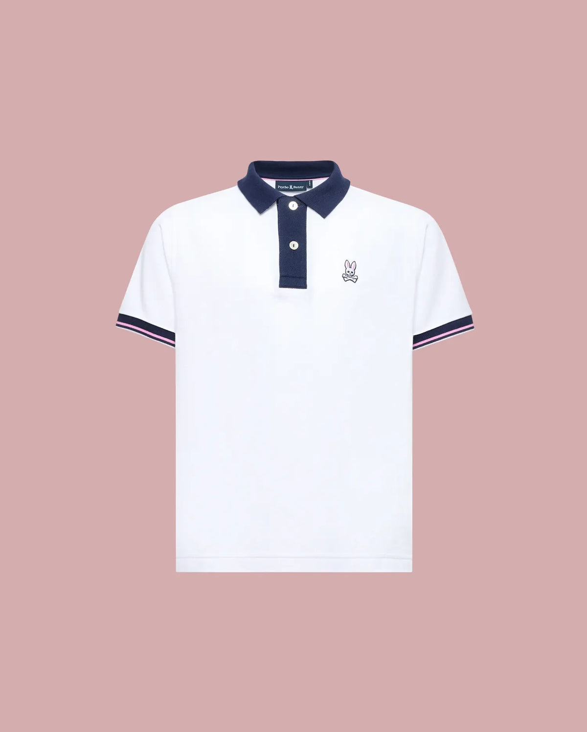 The Psycho Bunny KIDS ARCHIVE CLASSIC BUNNY PIQUE POLO (KT0100010) is a white, short-sleeve Pima cotton shirt with a navy collar and trim, three dark buttons, and an embroidered Bunny logo on the left chest, shown on a pale pink background.