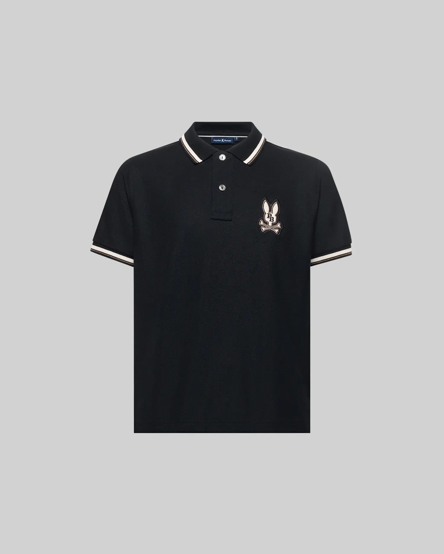 The Psycho Bunny KIDS WADE PIQUE POLO (KT0100032) is a black Pima cotton polo with colorblock tipping on the collar and sleeves, plus an embroidered cartoon rabbit logo on the left chest, shown on a light gray background.