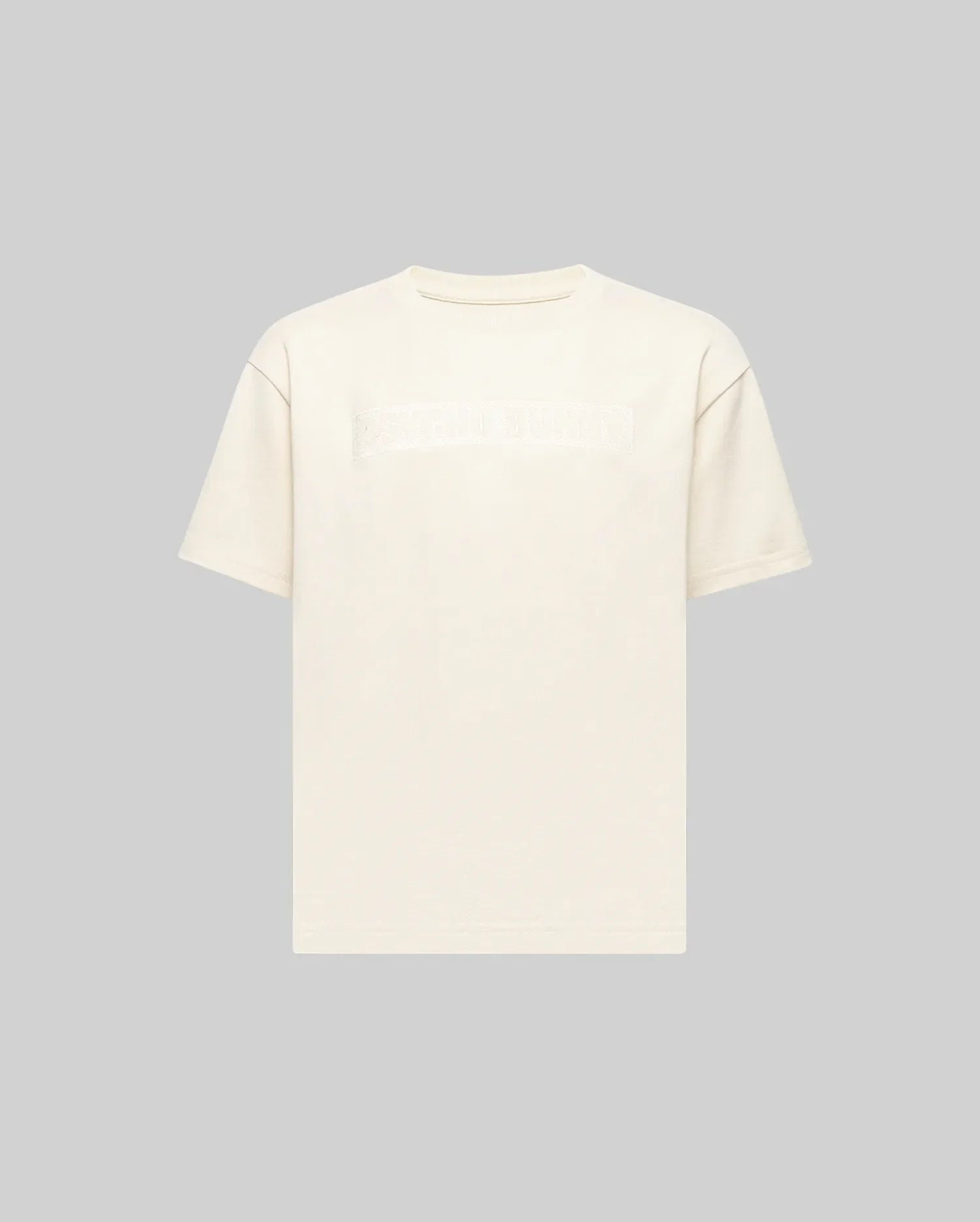 The KIDS ZAYN OVERSIZED GRAPHIC TEE (KT0200001) by Psycho Bunny is a relaxed-fit, off-white, short-sleeve 100% cotton tee featuring a subtle chest patch with indistinct text, shown on a light grey background.