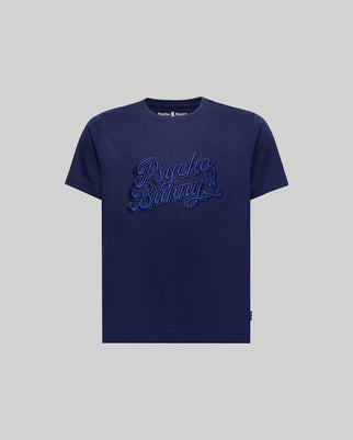 The KIDS ELIAS GRAPHIC TEE (KT0200013) by Psycho Bunny is a navy blue Pima cotton t-shirt featuring bold "Psycho Bunny" script embroidery on the chest in a retro style, displayed on a plain grey background.