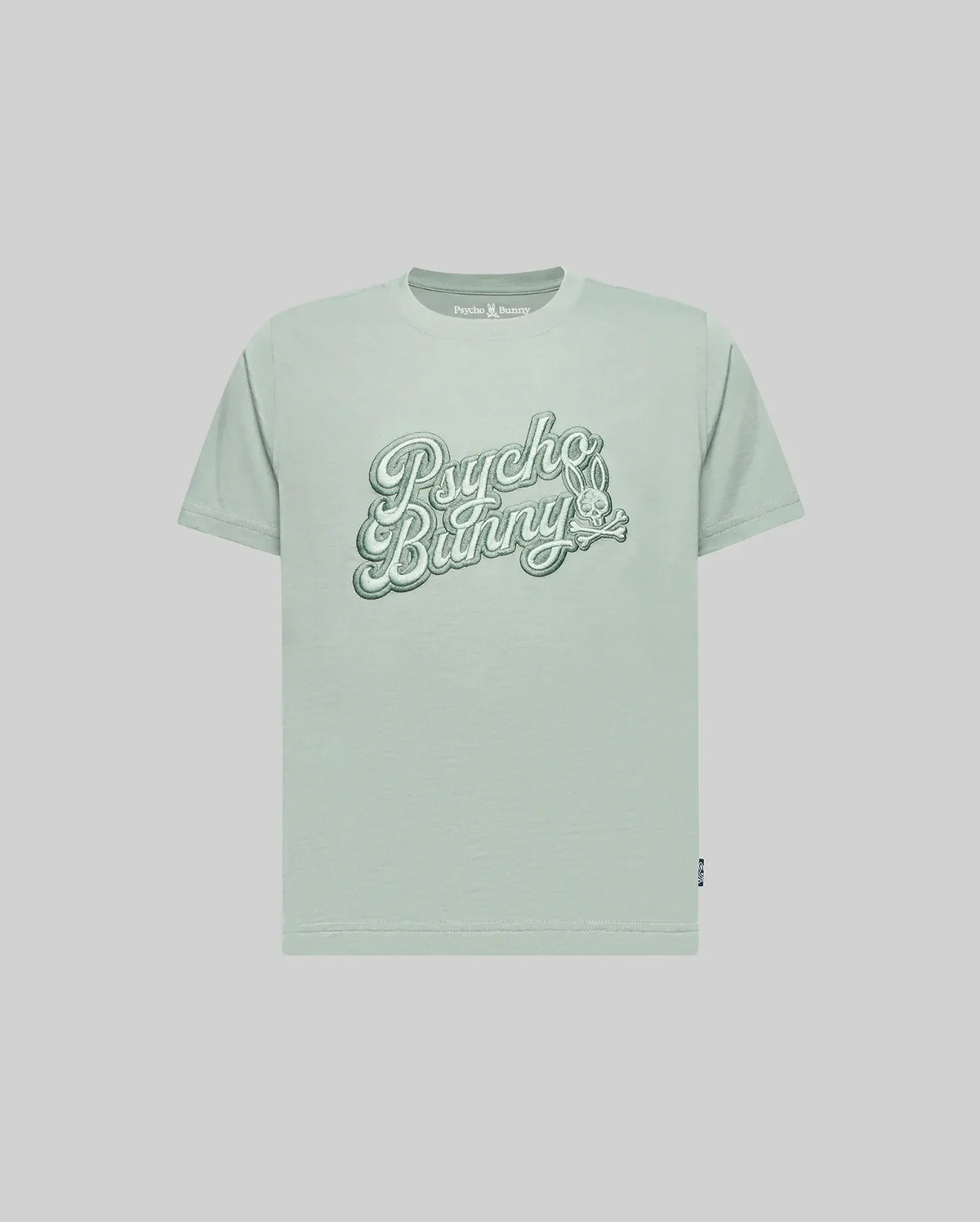 The KIDS ELIAS GRAPHIC TEE (KT0200013) by Psycho Bunny is a light green Pima cotton short-sleeve shirt with large retro "Psycho Bunny" script and a small bunny graphic on the chest, shown against a plain light background.