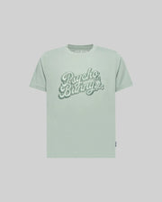 The KIDS ELIAS GRAPHIC TEE (KT0200013) by Psycho Bunny is a light green Pima cotton short-sleeve shirt with large retro "Psycho Bunny" script and a small bunny graphic on the chest, shown against a plain light background.