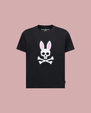 The Psycho Bunny KIDS ARCHIVE BUNNY GRAPHIC TEE (KT0200019) is a black Pima cotton t-shirt with a skull and crossbones bunny graphic with pink ears, shown on a solid light pink background.