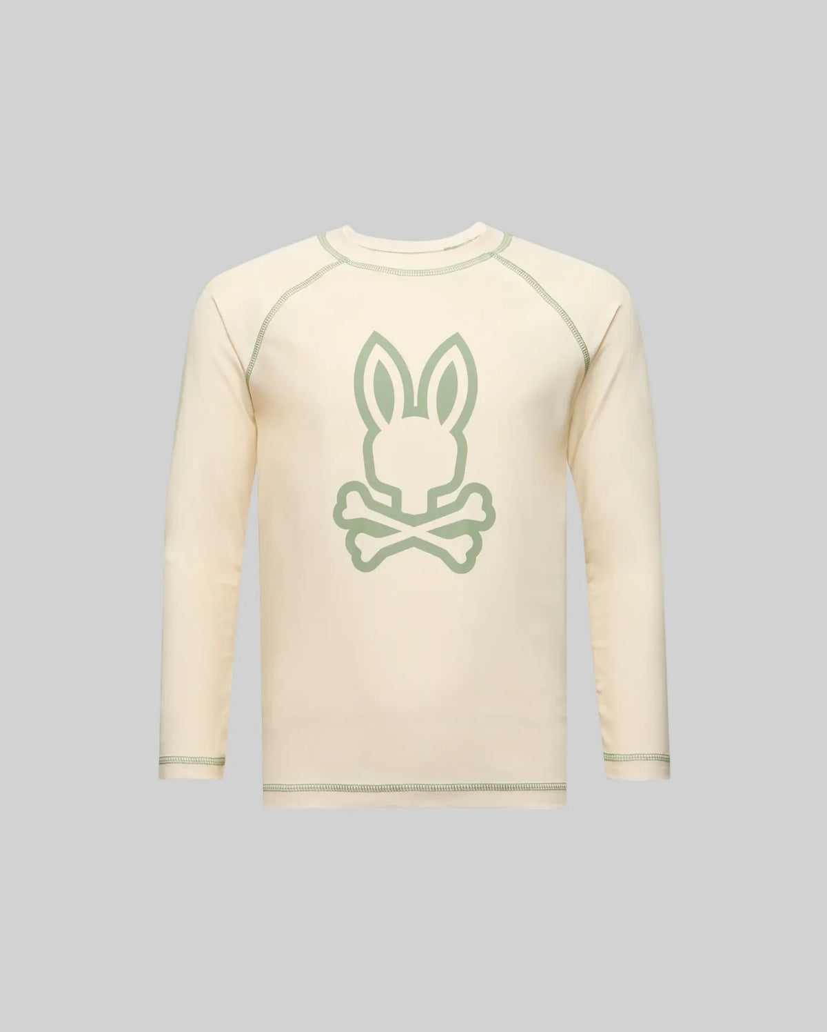 The Psycho Bunny KIDS LONG SLEEVE RASHGUARD - KT0200027 is cream-colored with a large light green Bunny head and crossed bones on the front, shown against a plain gray background.