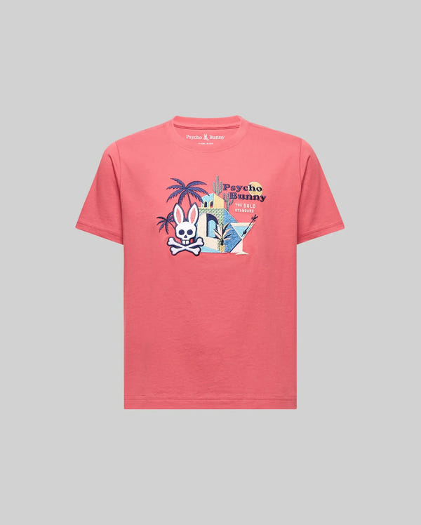 The Psycho Bunny KIDS SHANE GRAPHIC TEE (KT0200090) is a pink Pima cotton short-sleeve shirt with a vibrant cartoon bunny, palm trees, and buildings graphic plus "Psycho Bunny" on the chest, shown on a plain gray background.