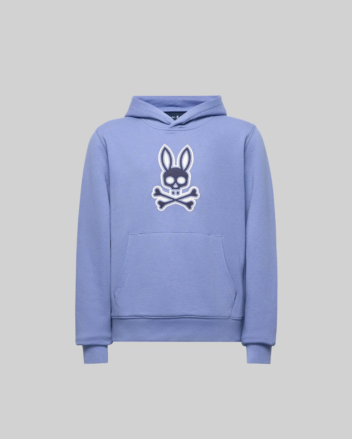 The Psycho Bunny KIDS RYDER EMBROIDERED BUNNY PATCH HOODIE (KT0500018) features a light purple color, front pocket, hood, and a large white and black embroidered bunny head above crossbones on the chest. Cozy style shown on gray background.