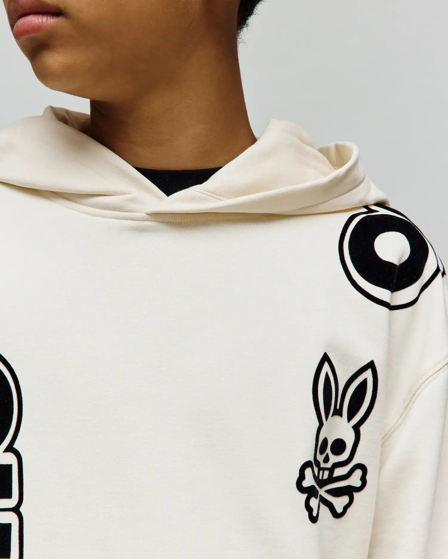 KIDS TOBY OVERSIZED HOODIE in cream, featuring large black Psycho Bunny skull and bold circular and letter-like graphic prints on the chest and shoulder, crafted from smooth knit.
