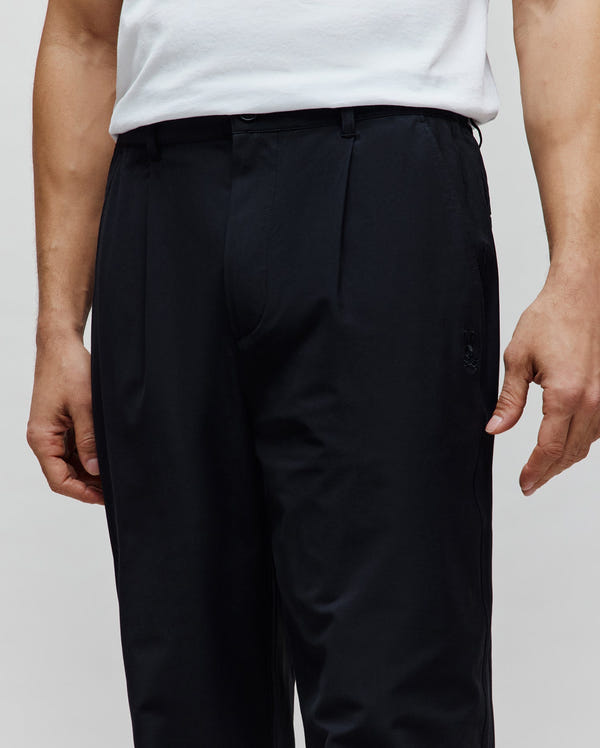 Mens Malik Wide Leg Pant in black, featuring a relaxed wide leg fit, front pleats, and a small tonal embroidered Psycho Bunny skull logo on the right hip.