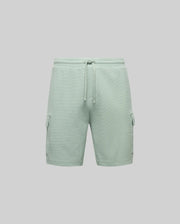 The Psycho Bunny MENS RON WAFFLE CARGO SHORT - MB0900012 features light green utility style, elastic waistband with drawstring, and side flap pockets on both legs, shown against a plain light gray background.