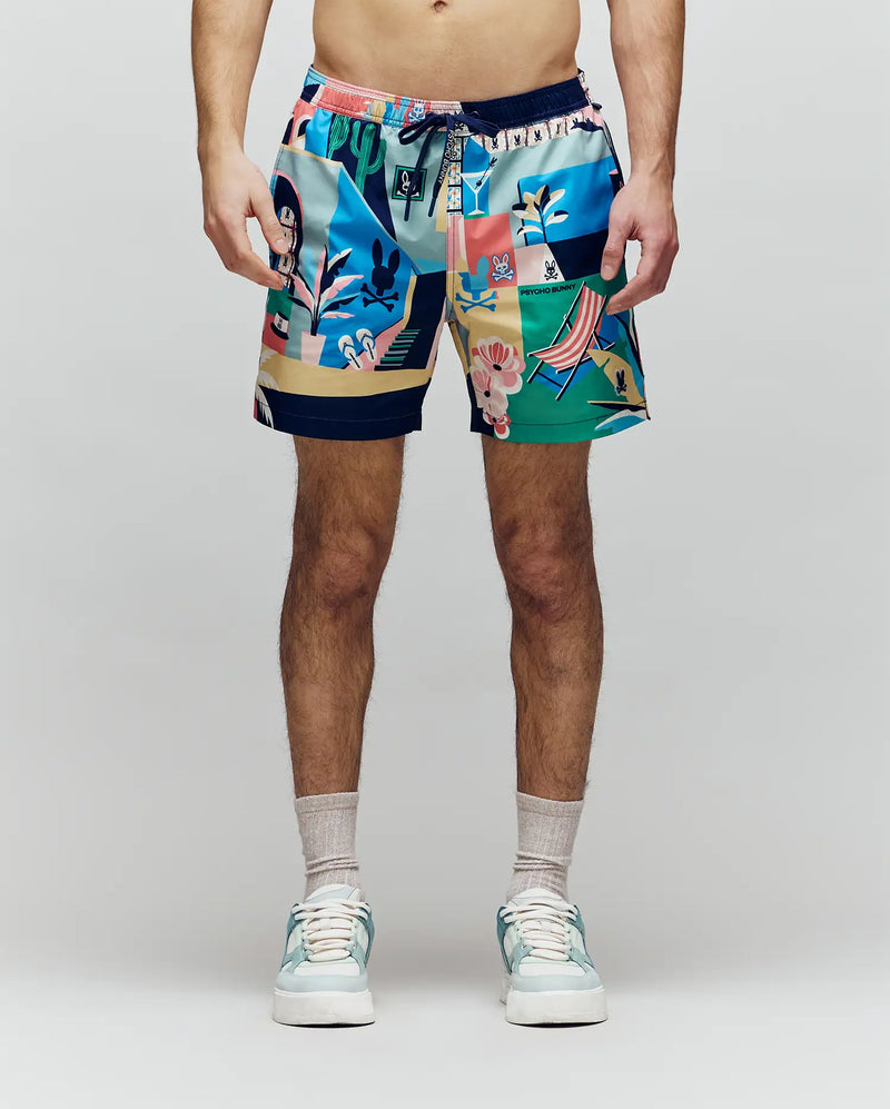 A person faces forward, shown from shoulders to feet against a light background, wearing Psycho Bunny MENS BLAISE SWIM TRUNK - MB1000028 with playful bunny logos, plus sandals and socks.