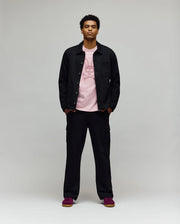 A man faces forward in a Psycho Bunny MENS AVEN KNIT SHACKET (MO1100035), black cargo pants, a light pink graphic tee, and red sneakers, all set against a plain gray backdrop.