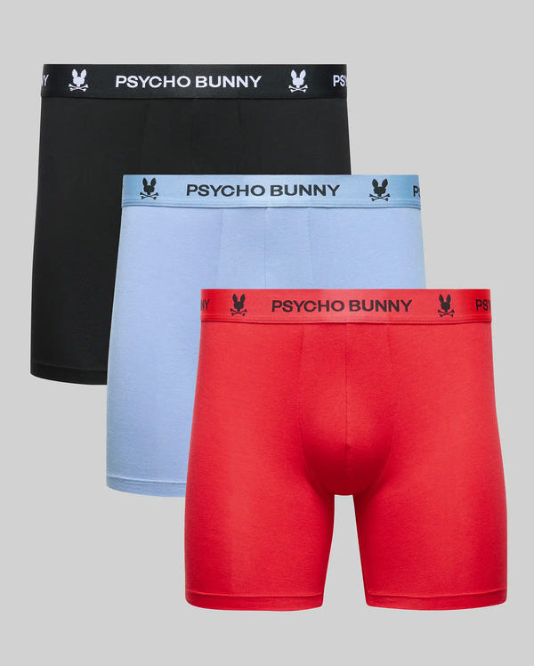 The Psycho Bunny MENS 3 PACK BOXER BRIEF (MO1400006) includes three cotton-modal pairs in black, light blue, and red. Each men's boxer brief features a branded waistband with the Psycho Bunny logo. Boxers are shown on a plain gray background.