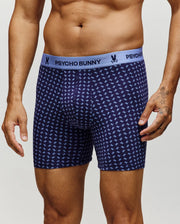 A man models the Psycho Bunny MENS SINGLE BOXER BRIEF - MO1400010 in navy, featuring a light blue waistband with the brand name and a soft Pima cotton fabric adorned with a repeating light blue bunny pattern for all-day comfort.