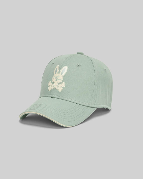 The Psycho Bunny MENS DEREK BASEBALL CAP - MO1500009 is a bold, light green cotton cap featuring a white bunny and crossbones logo on the front, shown against a plain gray background.