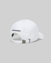 The Psycho Bunny MENS MISCHIEF BASEBALL CAP (MO1500015) is a white 100% cotton cap, shown from the back with "PSYCHO BUNNY" embroidered in black and an adjustable metal clasp strap against a plain light gray background.