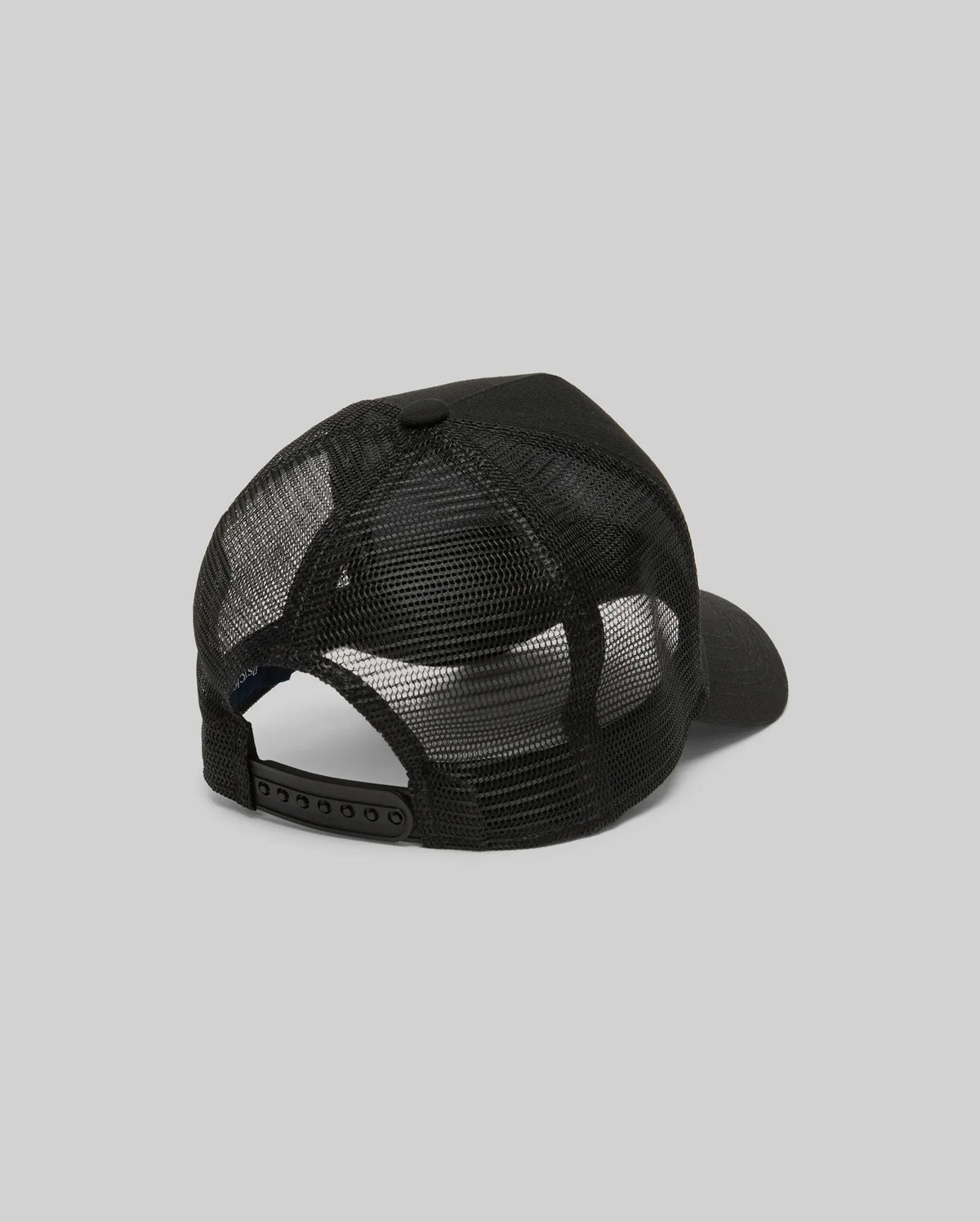 The Psycho Bunny MENS RYDER TRUCKER CAP (MO1500030) in black mesh and cotton twill is shown from the back, featuring an adjustable snapback closure and curved brim against a plain gray background.