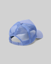 The Psycho Bunny MENS RYDER TRUCKER CAP (MO1500030), in light blue cotton twill with a mesh back and adjustable snapback, is shown angled to display its back and side against a plain gray background.