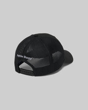 The MENS DARIO TRUCKER CAP (MO1500044) by Psycho Bunny is shown from the back in black mesh, with "Psycho Bunny" embroidered in white above the adjustable snap-back strap. The breathable cap contrasts against a light gray background.