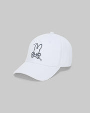 The Psycho Bunny MENS CYRUS BASEBALL CAP - MO1500045 is a white cap with an embroidered rabbit head above crossed carrots on the front, capturing coastal charm against a plain grey background.